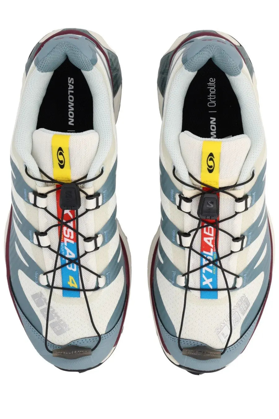 Salomon unisex sneaker in white and gray with black laces yellow and blue accents and textured rubber outsole
