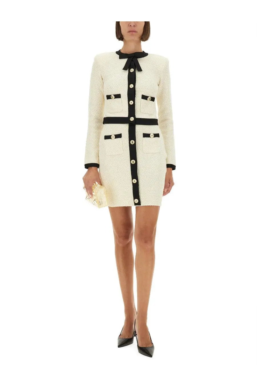 Cream-colored tweed mini dress with black trim buttons and bow at the neckline paired with self-portrait white sequin knit skirt