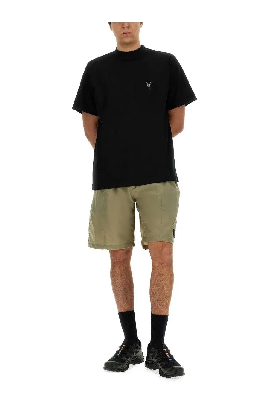 Black short-sleeved t-shirt with small white embroidered logo on chest paired with south2 west8 men’s beige nylon bermuda shorts