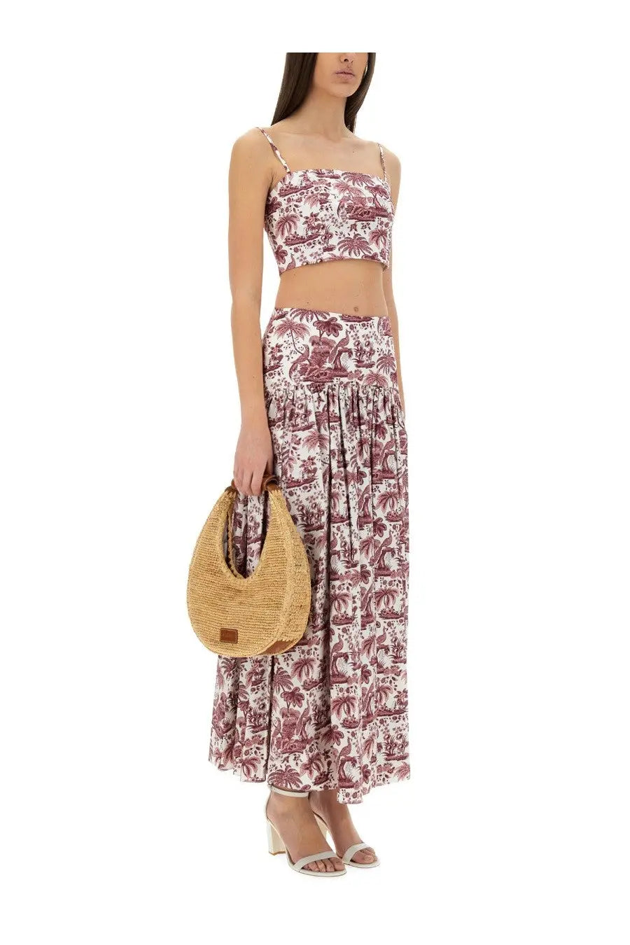 A woven straw handbag with crescent shape and small brown leather patch paired with staud women’s tank top federico red