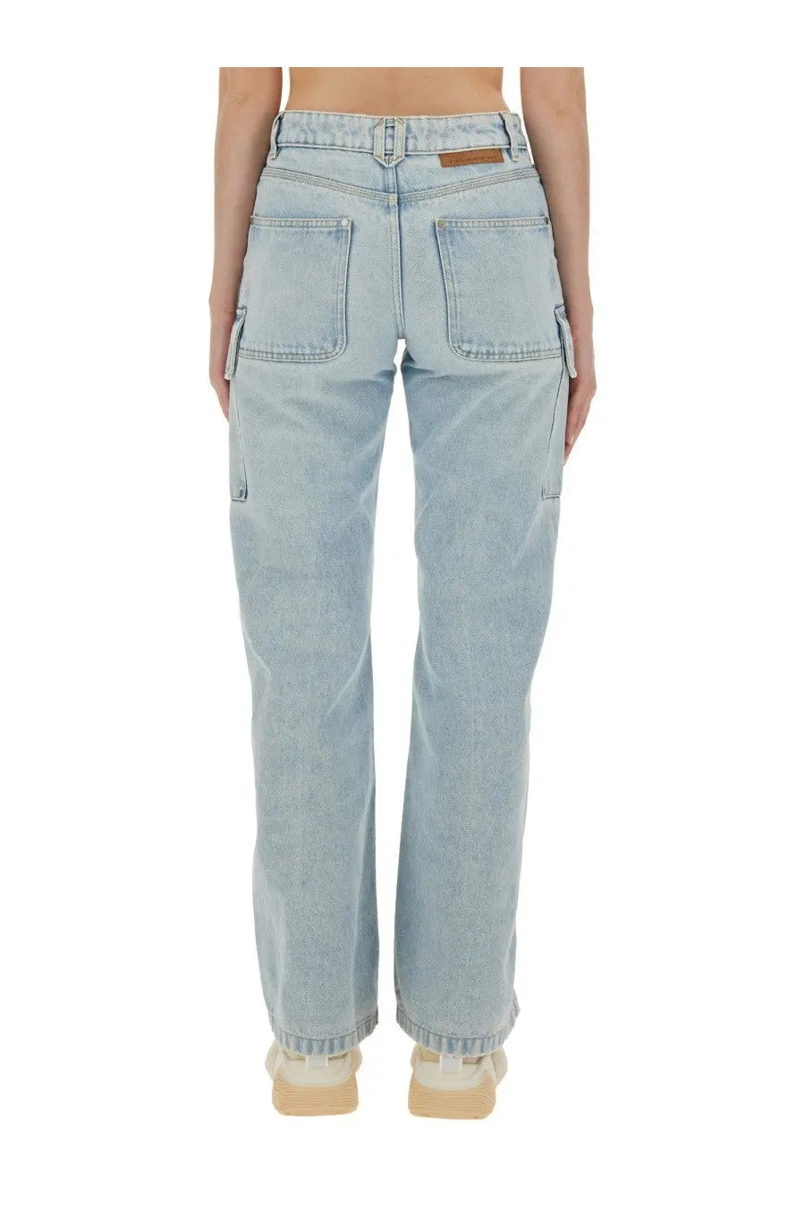 Back view of stella mccartney women’s light-wash denim cargo jeans with two back pockets and brown leather patch