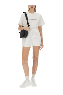 Black leather crossbody bag with gold-tone hardware minimalist design paired with stella mccartney women’s white cotton shirt