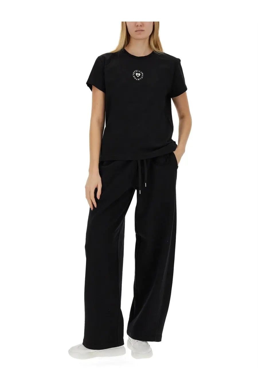 Black short-sleeved t-shirt with small white circular logo on chest paired with stella mccartney womens jogging pants black