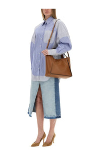 Tan leather tote bag with embossed logo and striped shoulder strap paired with stella mccartney women’s mixed stripe shirt blue