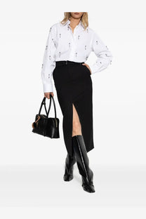 Black leather handbag with gold-tone hardware and tassel detail paired with Stella McCartney women’s white shirt
