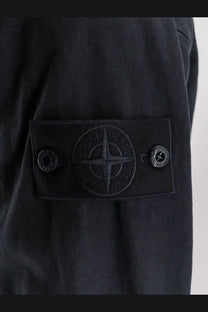 Black stone island patch with embroidered compass logo and two snap buttons on stone island men’s blue cotton linen shirt