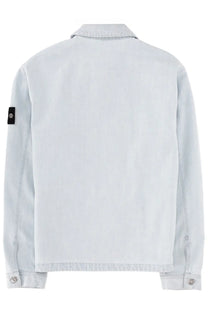 Stone Island men’s light blue denim jacket with black sleeve patch featuring a silver emblem