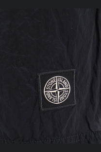 Black stone island patch with white compass rose logo on fabric of stone island mens econylon swim trunks blue