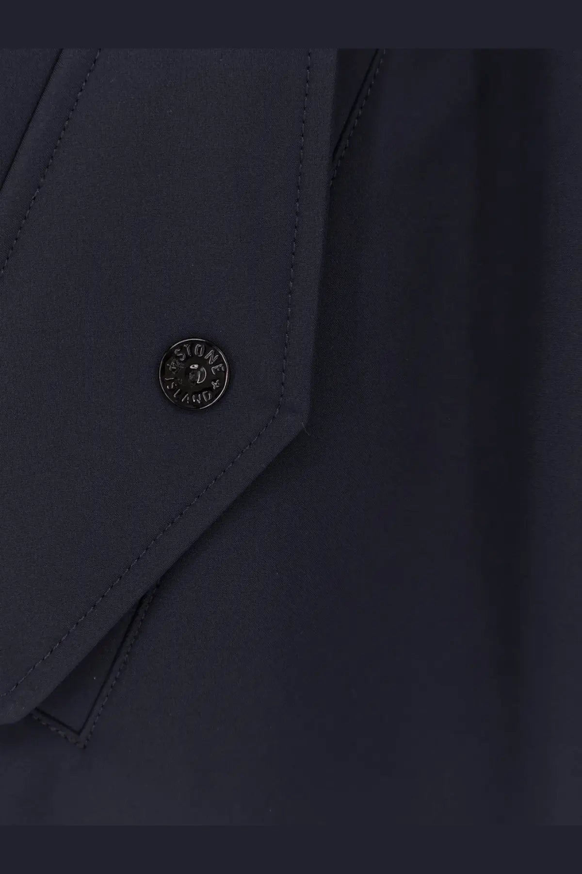 Dark navy stone island button with circular metallic emblem on men’s light soft shell edye technology jacket blue