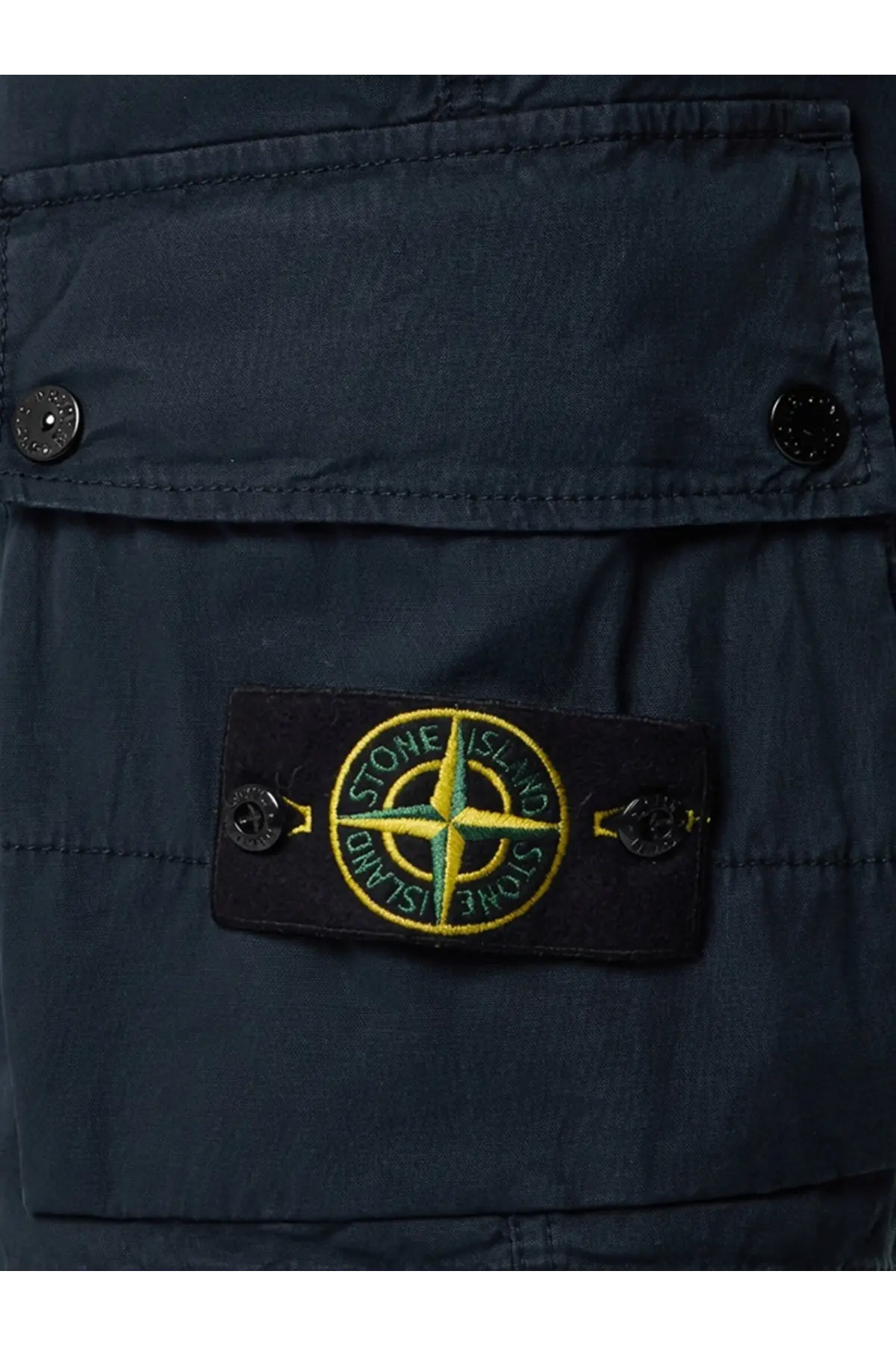 Dark navy stone island patch with yellow and green embroidered compass rose on black fabric on blue organic cotton shorts