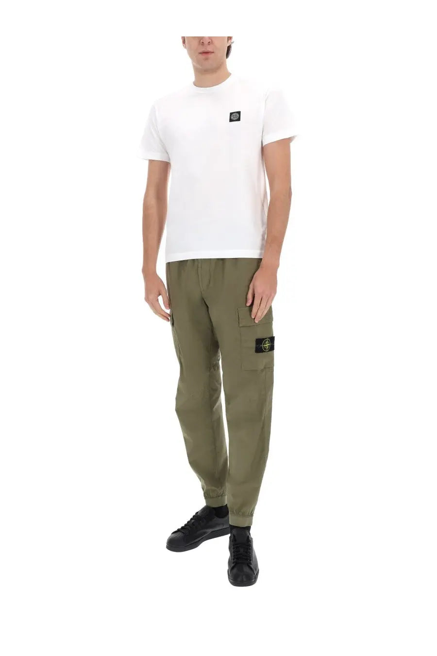 White cotton t-shirt featuring a black stone island logo patch on the left chest paired with parachute green pants