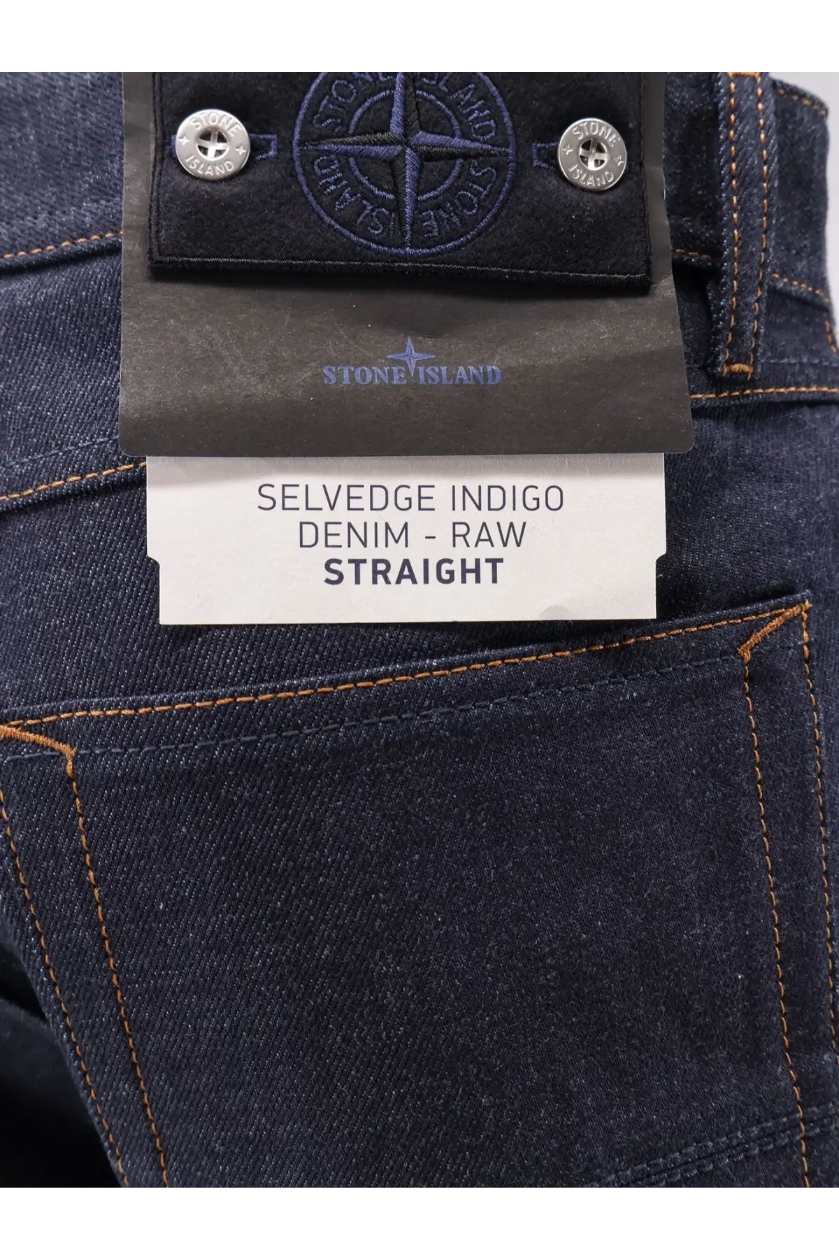 Stone Island men’s selvedge indigo jeans in dark blue raw denim with orange stitching and a black branded label