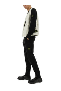 Stone Island men’s vest in black and off-white stone with yellow logo patch worn over long-sleeved black shirt