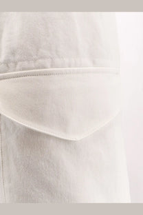 A close-up of a light-wash denim pocket on studio nicholson men’s cotton bermuda shorts salt with stitched edges