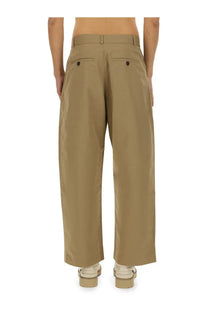 Studio nicholson men’s slim curved beige pants shown from back with khaki wide-leg design and dark brown back pocket buttons