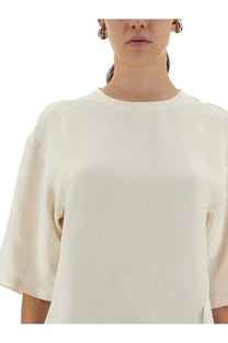 Studio nicholson women’s cream-colored loose-fitting short-sleeved top with round neckline and asymmetrical design