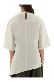 Studio nicholson women’s cream-colored loose-fitting blouse with short sleeves and central back slit shown from back side