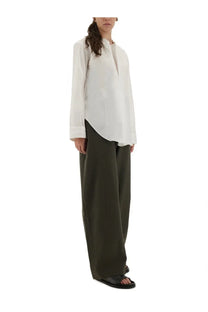 Studio Nicholson women’s white minimalist long-sleeved blouse with high neckline and asymmetrical hemline