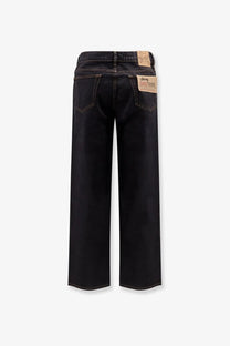 Back side of stussy men’s classic black denim jeans with wide-leg cut and brown leather patches on back pockets