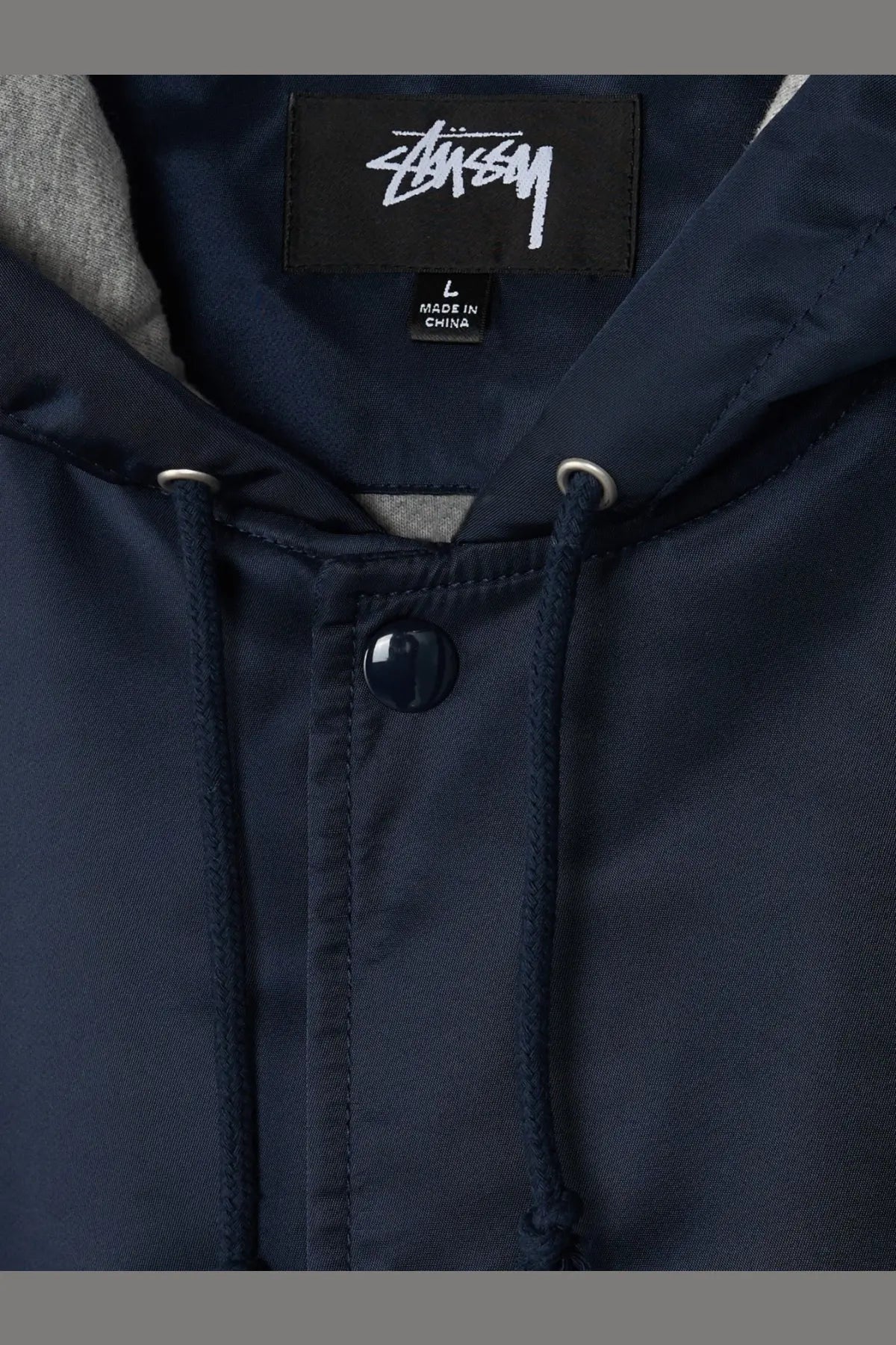 Stussy men’s nylon jacket blue featuring a dark navy hoodie with black brand label and matching drawstrings