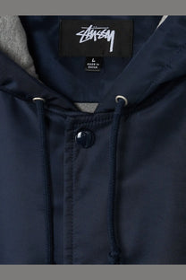 Stussy men’s nylon jacket blue featuring a dark navy hoodie with black brand label and matching drawstrings