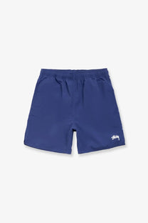 Navy blue Stussy men’s nylon swim trunks with a white logo on the lower right leg for swimming and beachwear