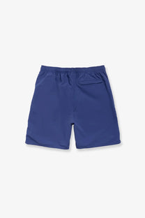 Navy blue stussy men’s nylon swim trunks in twilight with elastic waistband and single back pocket shown from the back