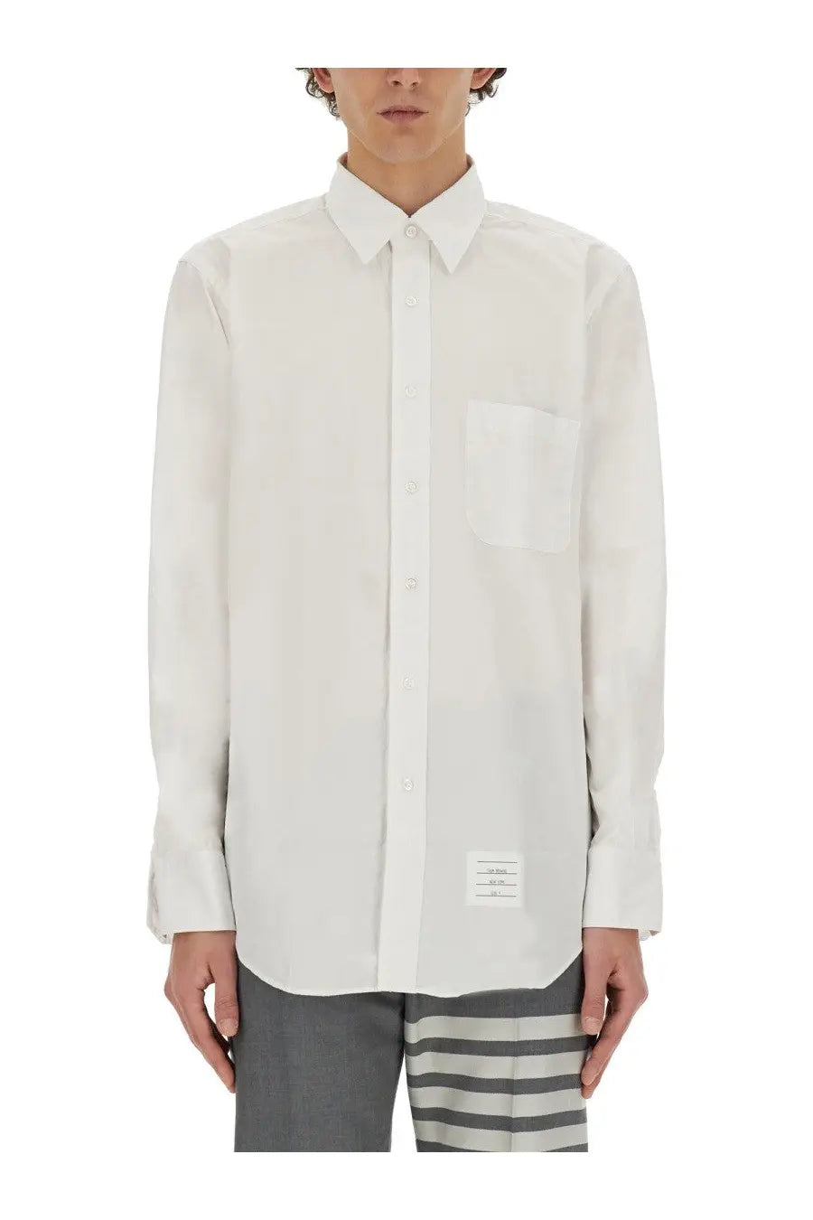 Thom Browne men’s white long-sleeved button down shirt with chest pocket and label at bottom hem