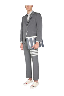 Thom Browne men’s classic gray pants with distinctive white navy blue and red stripes and matching striped clutch