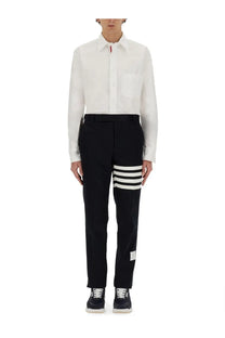 Black cotton Thom Browne trousers with three bold white stripes on the lower leg and a branded label at the hem