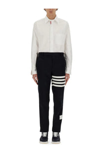 Black trousers with three bold white horizontal stripes and branded label at hem paired with thom browne men’s cotton shirt white