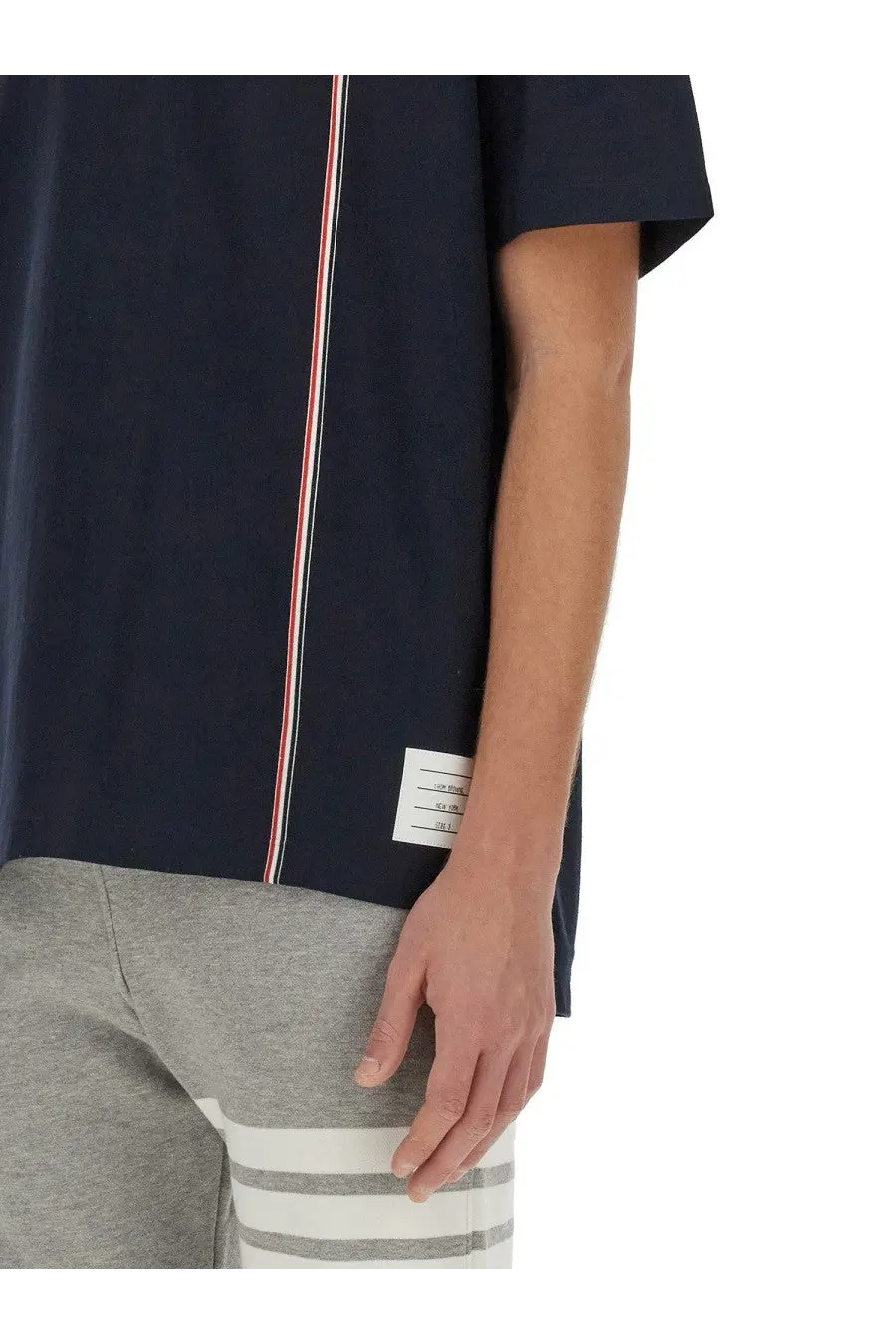 Thom Browne men’s navy blue jersey shirt with short sleeves and red white blue vertical stripe along side seam