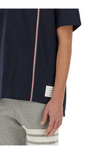 Thom Browne men’s navy blue jersey shirt with short sleeves and red white blue vertical stripe along side seam