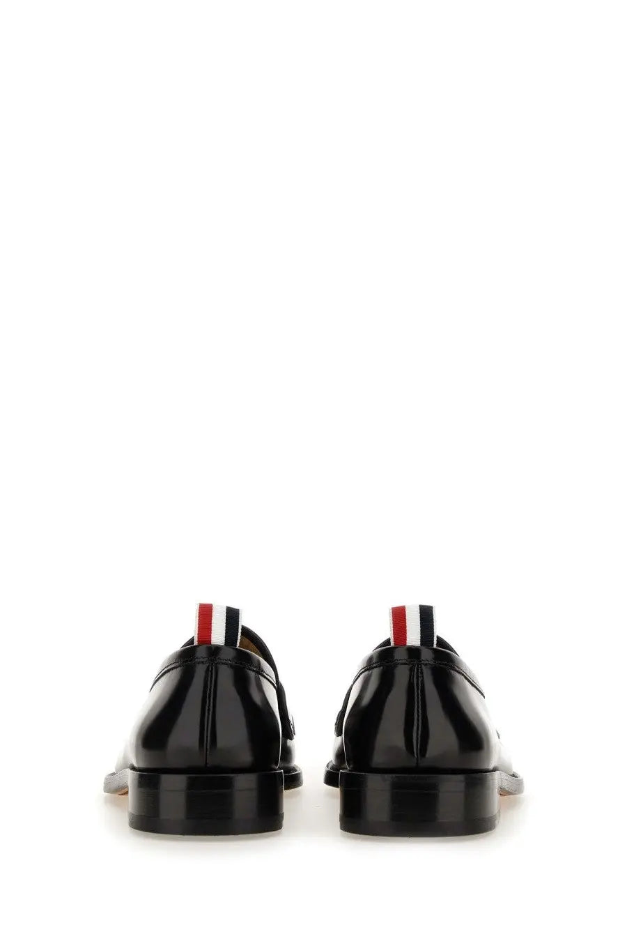 Thom browne men’s black patent leather loafers with red white and blue striped pull tab visible from the back
