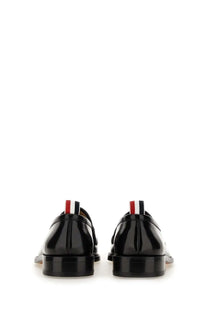 Thom browne men’s black patent leather loafers with red white and blue striped pull tab visible from the back