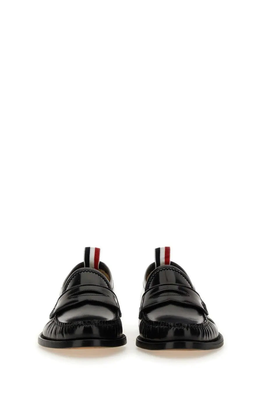 Thom Browne men’s black patent leather loafers with glossy finish and red white and blue striped pull tabs visible from the back