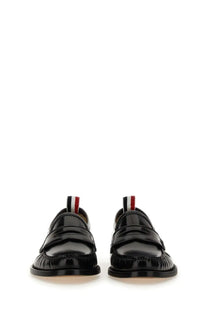 Thom Browne men’s black patent leather loafers with glossy finish and red white and blue striped pull tabs visible from the back