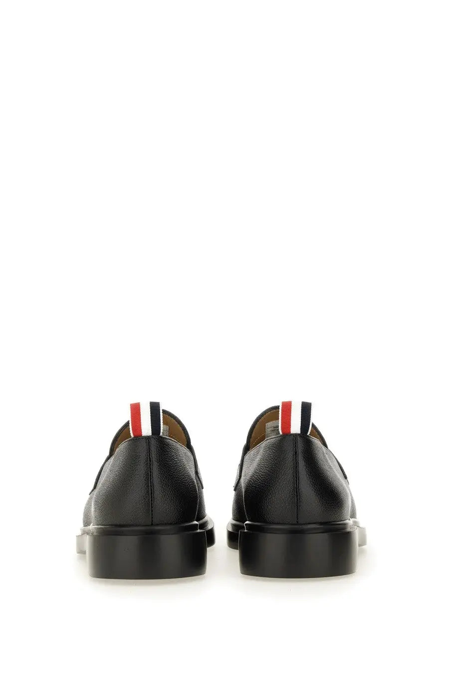 Back view of thom browne men’s black leather moccasin penny loafer with red white and blue striped tab at heel