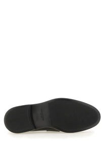 Black rubber sole of thom browne men’s moccasin penny black with textured grip pattern and embossed brand logo near heel