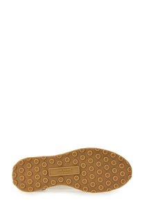 Tan rubber sole with circular tread and rectangular thom browne new york label on the back of men’s tech runner blue sneaker