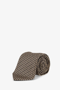 A neatly rolled tom ford men’s silk tie in beige with black herringbone pattern