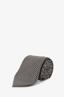 A neatly rolled tom ford men’s silk tie in black and white herringbone pattern