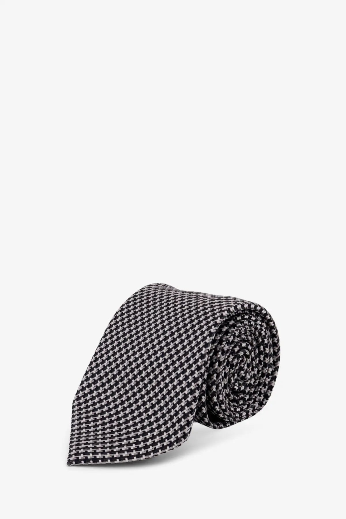 A neatly rolled tom ford men’s silk tie in black and white houndstooth pattern with grey tones