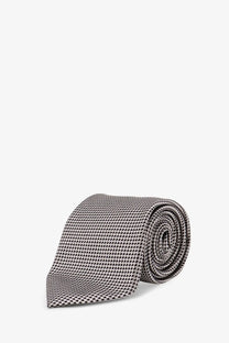 A sleek rolled tom ford men’s silk tie silver in gray with a subtle black and white houndstooth pattern