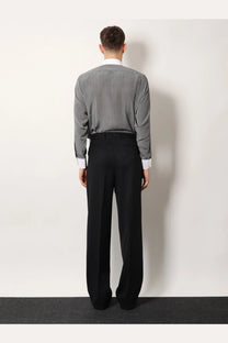 A man wearing Tom Ford men’s black wool trousers paired with a gray patterned long-sleeve shirt with white cuffs