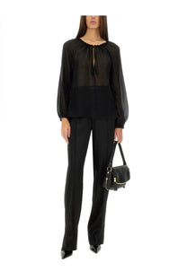 Tom ford women’s sheer black silk blouse with ruffled neckline and long sleeves paired with black trousers