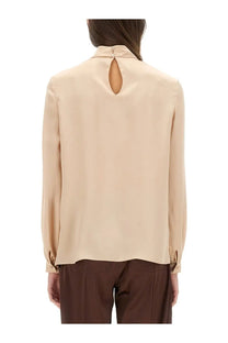 Beige satin blouse with keyhole back detail and buttoned cuffs shown from the back in tom ford women’s silk pink collection