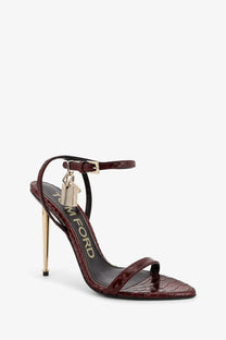 Tom Ford women’s laminated leather sandals in burgundy with crocodile embossing and gold-tone stiletto heel and ankle strap