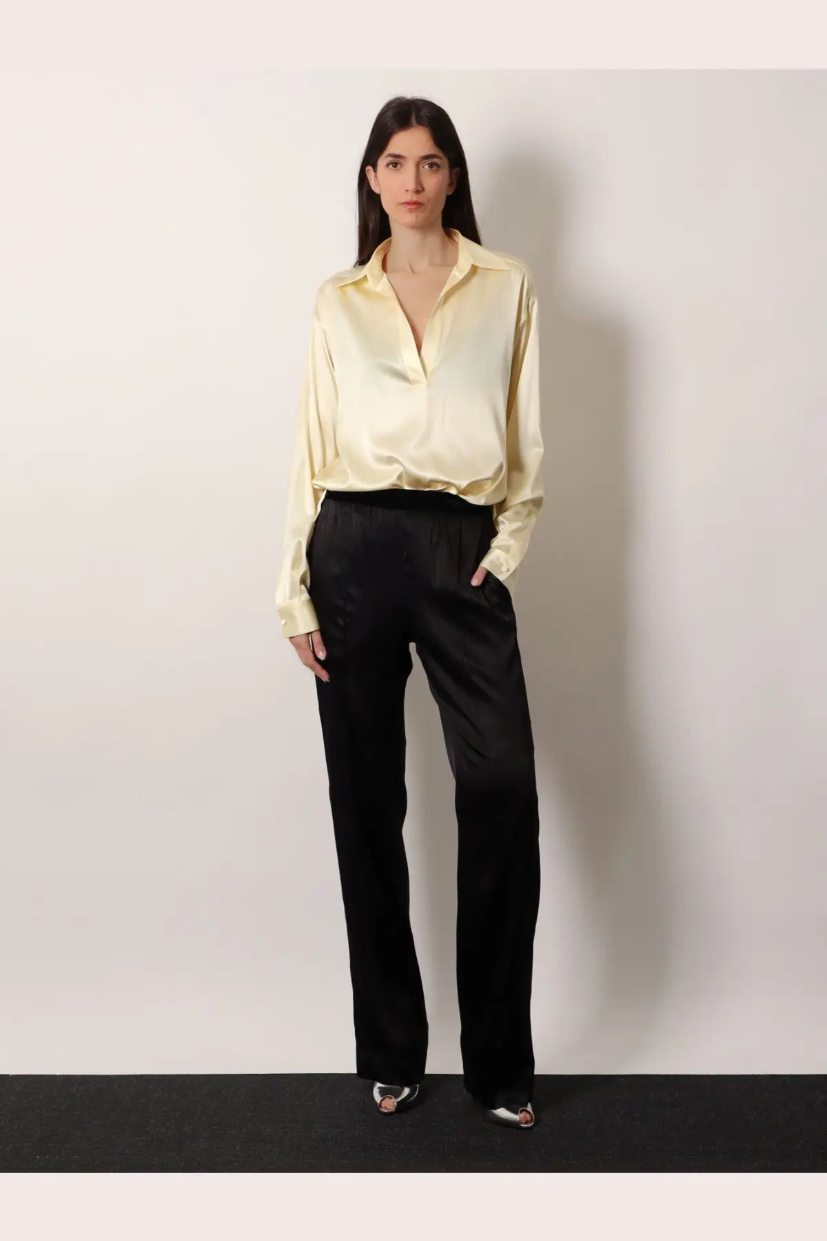 A pale yellow satin blouse with classic collar and long sleeves paired with tom ford stretch satin black trousers
