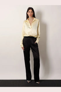A pale yellow satin blouse with classic collar and long sleeves paired with tom ford stretch satin black trousers